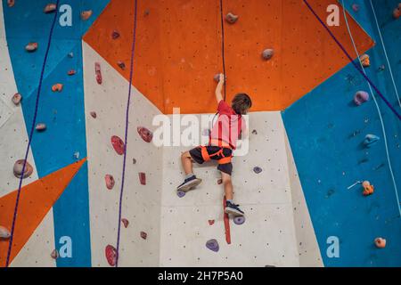 Boy at the climbing wall without a helmet, danger at the climbing wall Stock Photo