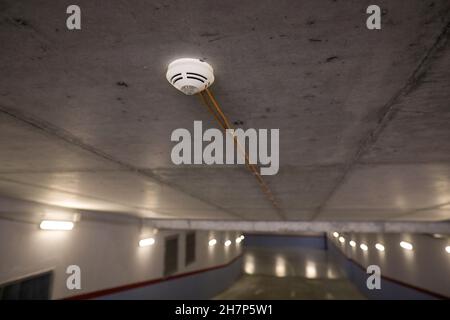 Shallow depth of field (selective focus) image with a smoke detector sensor  inside an underground parking. Stock Photo
