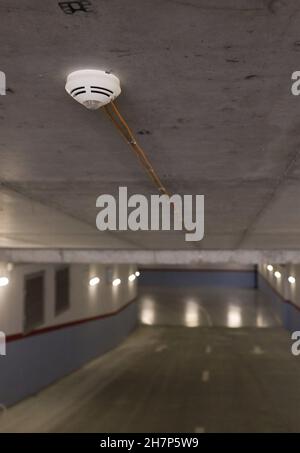 Shallow depth of field (selective focus) image with a smoke detector sensor  inside an underground parking. Stock Photo