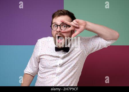 Positive man in round glasses, a shirt and a bow tie is dancing, he makes strange, funny movements and opens mouth as if singing.  Stock Photo