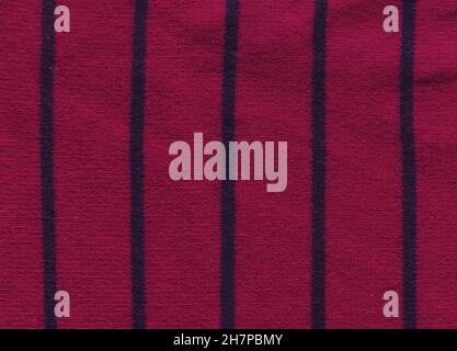Magneta knitted background with copy space. Fabric poppy red colored colored texture with black stripes. Stock Photo