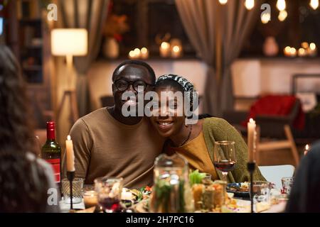 Portrait of happy African couple smiling at camera while sitting at dining table in the room Stock Photo