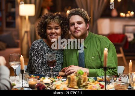 Portrait of multiethnic young couple smiling at camera while having a romantic dinner at the table Stock Photo