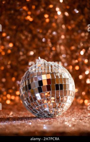 silver disco ball on rose gold sequin background. Holiday season Christmas and New Year retro party Stock Photo