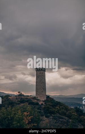 Large ancient stone tower stands on a hill in the forest. Mountain view ...