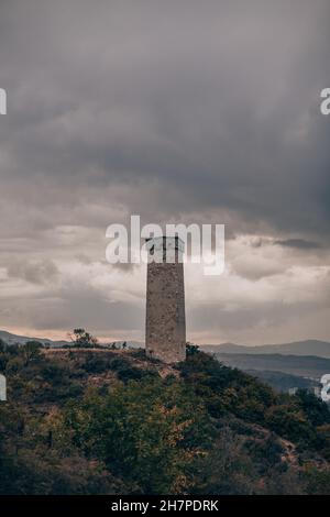 Large ancient stone tower stands on a hill in the forest. Mountain view ...