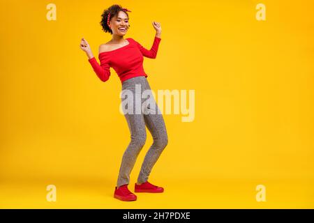 Photo of funky charming positive lady dance wear pin-up outfit shiny pants isolated yellow color background Stock Photo