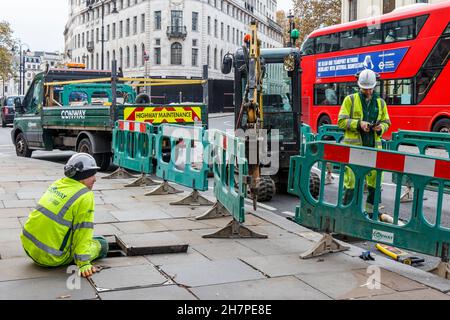 Two workmen mending utilities on the Strand, Charing Cross, London, UK Stock Photo