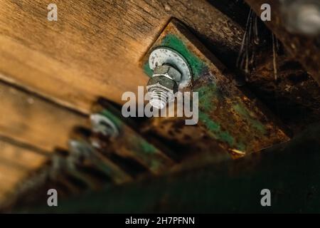 Nut with screw holds the old planks of a wooden bridge, detail. Stock Photo
