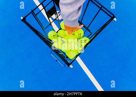 Valencia, Spain - April 26, 2021: A tennis player picks up a Dunlop tennis ball from a basket during a practice. Stock Photo