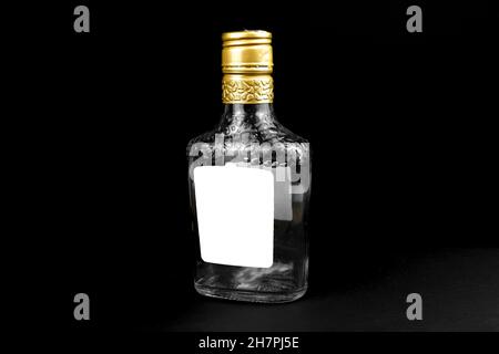 Mockup label on empty glass bottle of whiskey, cognac or vodka on a black background. Template, copy space Stock Photo