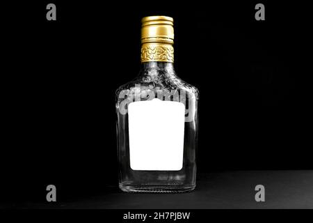 Mockup label on empty glass bottle of whiskey, cognac or vodka on a black background. Template, copy space Stock Photo