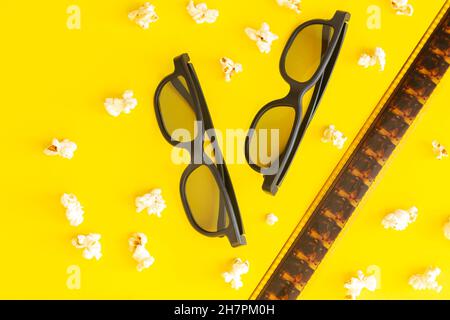 Movie time concept, cinema background with popcorn, 3d glasses and filmstrip top view on yellow table Stock Photo