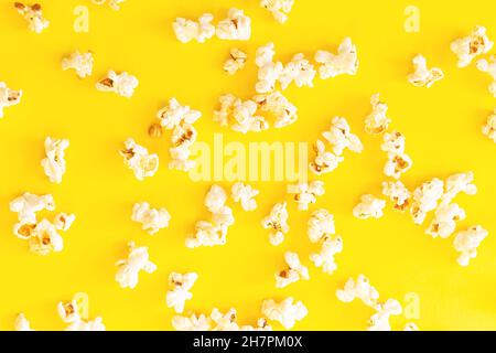 Crunchy scattered popcorn on yellow background top view. Best food for cinema Stock Photo