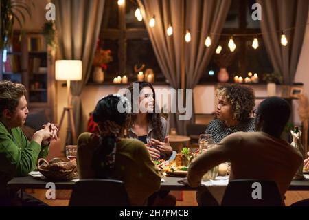 Group of friends talking to each other at dining table during a meeting at dinner party at home Stock Photo
