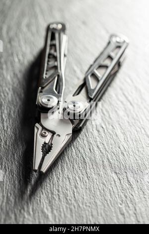 Multi-tools pliers with other tools and knife. Multifunction pliers on stone table. Stock Photo