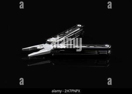 Multi-tools pliers with other tools and knife. Multifunction pliers on black background. Stock Photo
