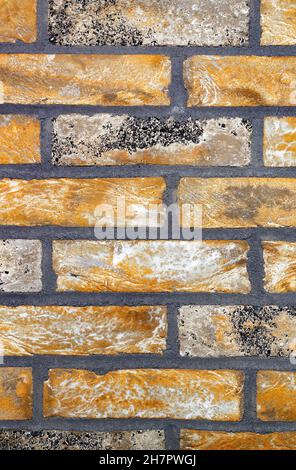 Background and texture of a wall of yellow-brown old brick with wide gray cement joints. Vertical image. Copy space. Stock Photo
