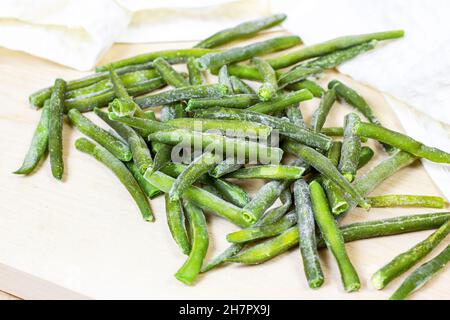 Frozen green beans pods on light wooden background. Stock Photo