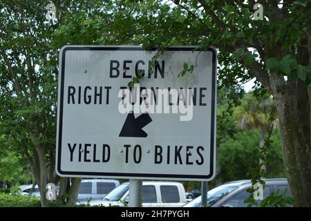 A sign indicates where a turn lane begins and warns about bicycles. Stock Photo