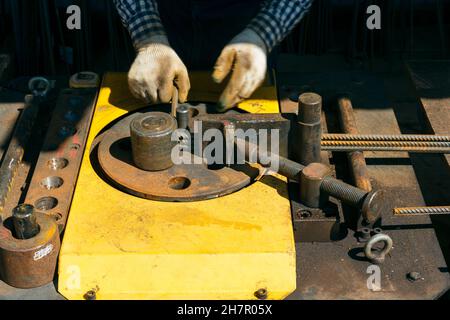 Hands of a worker at work at the armature bending machine. Rebars with rebar bending machine in the site. Worker using bending rebar machine for reinf Stock Photo