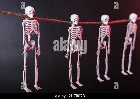 Four skeletons suspended by the neck on a rope with silhouettes on a ...