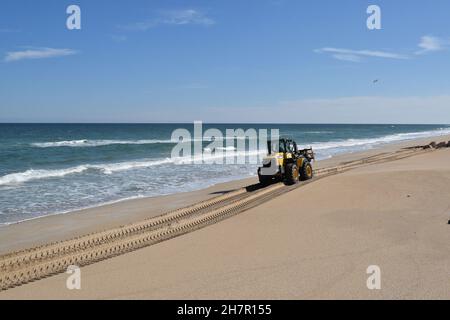 Heavy equipment moves a rock down the beach. Stock Photo