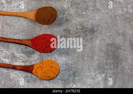 Looking down on spoons of colourful spices against a grey background, with copy space Stock Photo
