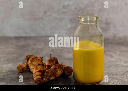 A studio photograph of turmeric root and plant based turmeric milk against a white background Stock Photo