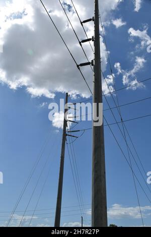 Cables attached to tall utility poles from many directions. Stock Photo