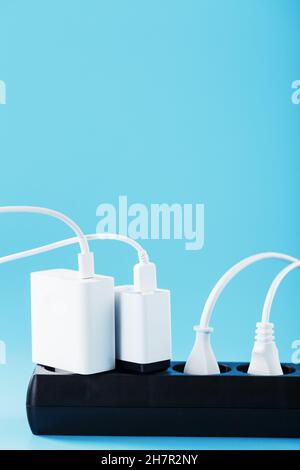 Surge protector with connected white wires of electrical appliances on a blue background. Free space Stock Photo