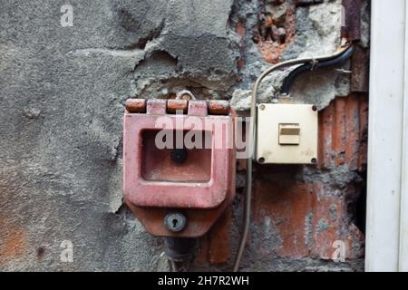 Closeup shot of an old dirty red switch of an emergency stop on a wall Stock Photo