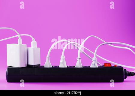 Surge protector with connected white wires of electrical appliances on a pink background. Free space Stock Photo