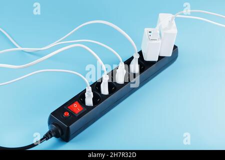 Surge protector with connected white wires of electrical appliances on a blue background. Free space Stock Photo