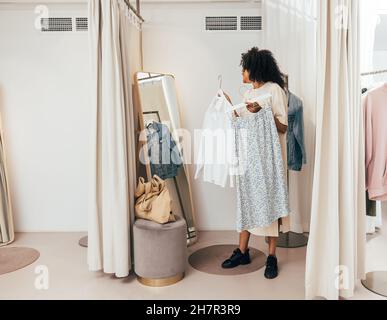 Young woman choosing clothes while standing in fitting room in a boutique Stock Photo