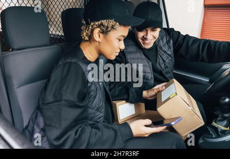 Two couriers sitting in van checking information on box for delivery Stock Photo