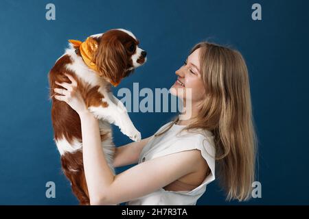 Side view of young woman holding her little dog in studio Stock Photo