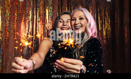 Two senior girlfriends having fun together holding sparklers Stock Photo
