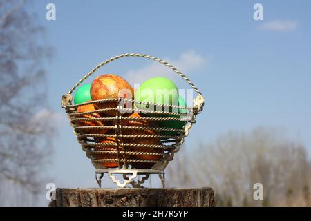 Bright colorful Easter eggs in a basket on birch tree stump Stock Photo