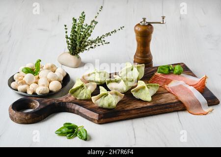 Dumplings stuffed with smoked ham and mushrooms on wooden serving board Stock Photo