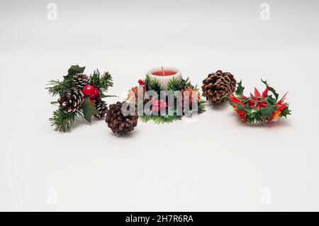 Plastic table-top or mantle-top Christmas decorations of a candle, pine cones, holly, and poinsettias. Stock Photo
