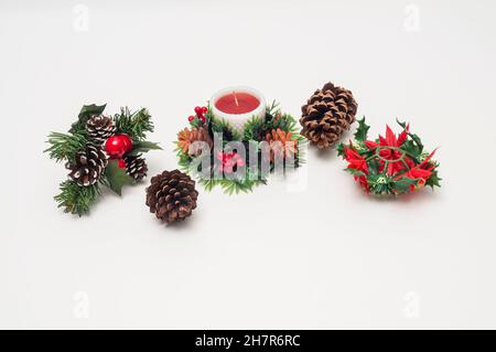 Plastic table-top or mantle-top Christmas decorations of a candle, pine cones, holly, and poinsettias. Stock Photo