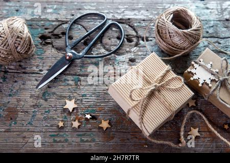 Two skeins of craft thread, scissors, two packed boxes, wooden stars lie on a wooden table Stock Photo