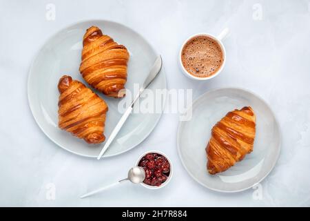 Croissants with jam and coffee. Two gray plates on a marble table. Top view, flat lay. A cup of hot chocolate in the morning for breakfast. French cul Stock Photo