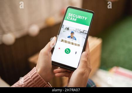 Delivery man ringing door bell on cctv secure camera system on mobile phone app Stock Photo