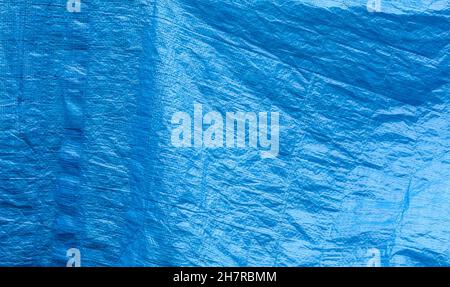 Simple blue plastic tarp, woven crumpled plain used protective industrial tilt curtain abstract background texture, object closeup, nobody, backdrop B Stock Photo