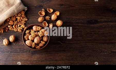 Walnut kernels and whole walnuts on a rustic old wooden table backlit Stock Photo
