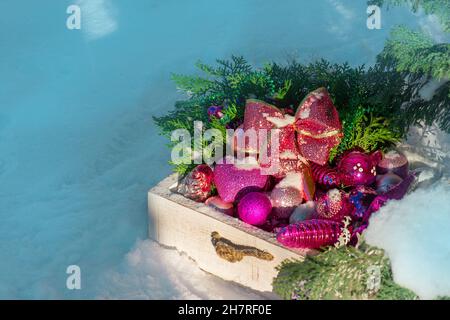 New Years photo zone with wooden box filled Christmas toys. Christmas  balls in a wooden box outdoors on blurred white background. Stock Photo