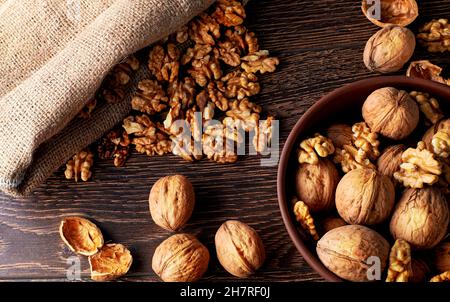 Walnut kernels and whole walnuts on a rustic old wooden table backlit Stock Photo