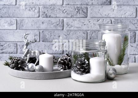 Interior for christmas with candles in a glass jar and concrete tray with candles, pine cones, fir branches and silver Christmas balls with a deer on Stock Photo